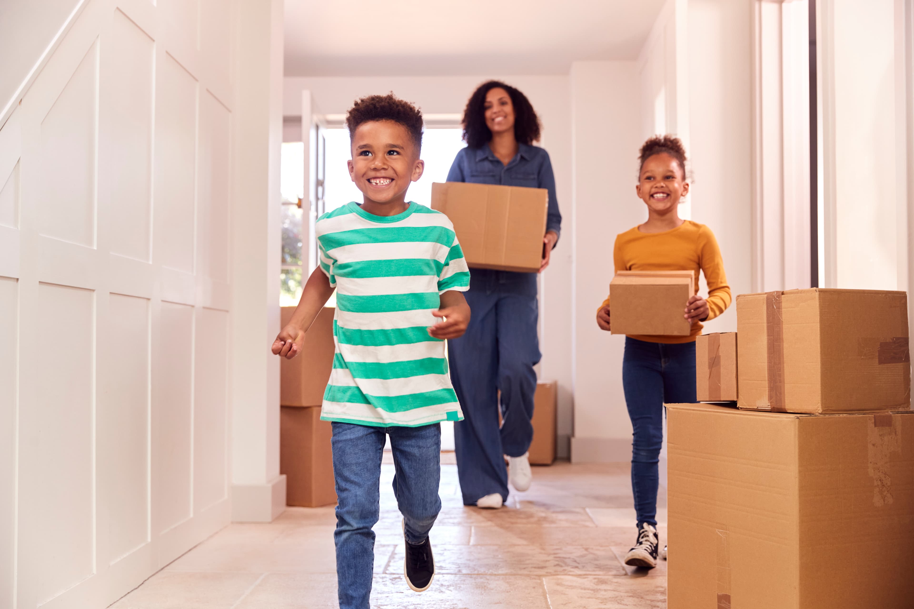Children helping mother carry boxes into new home