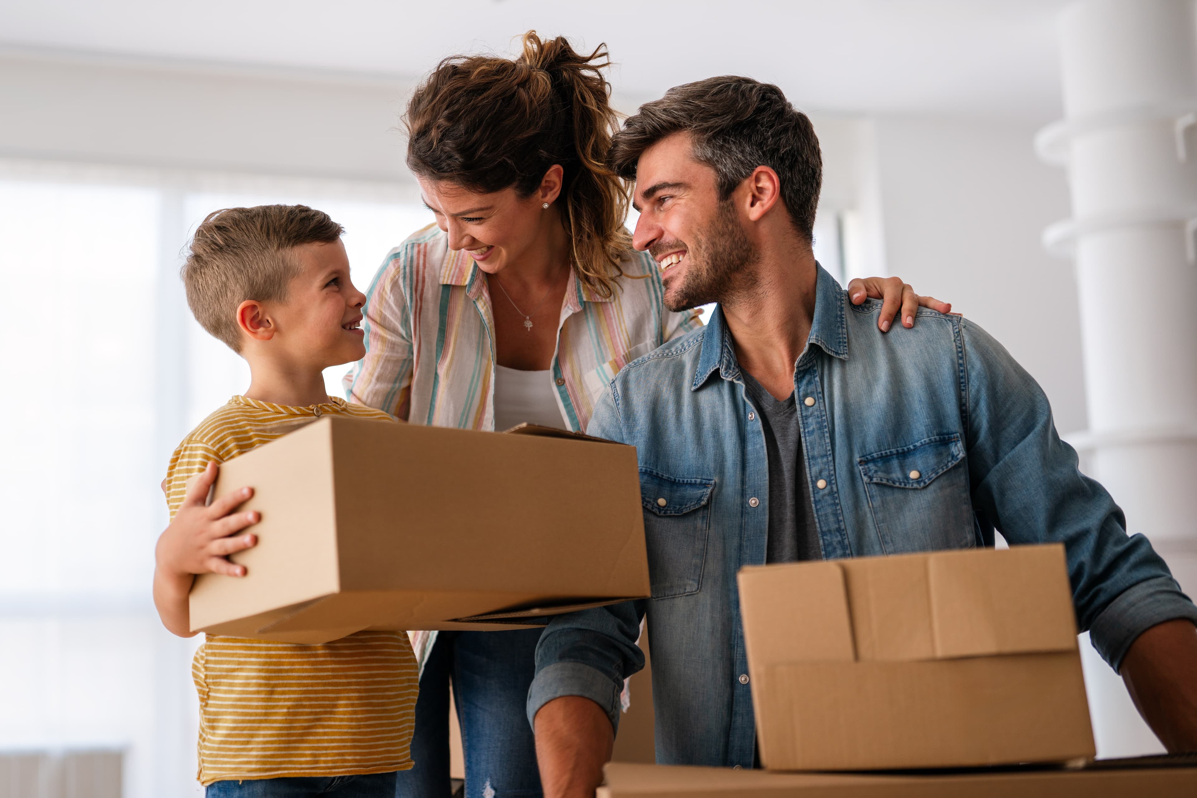 Happy family with cardboard boxes in new house