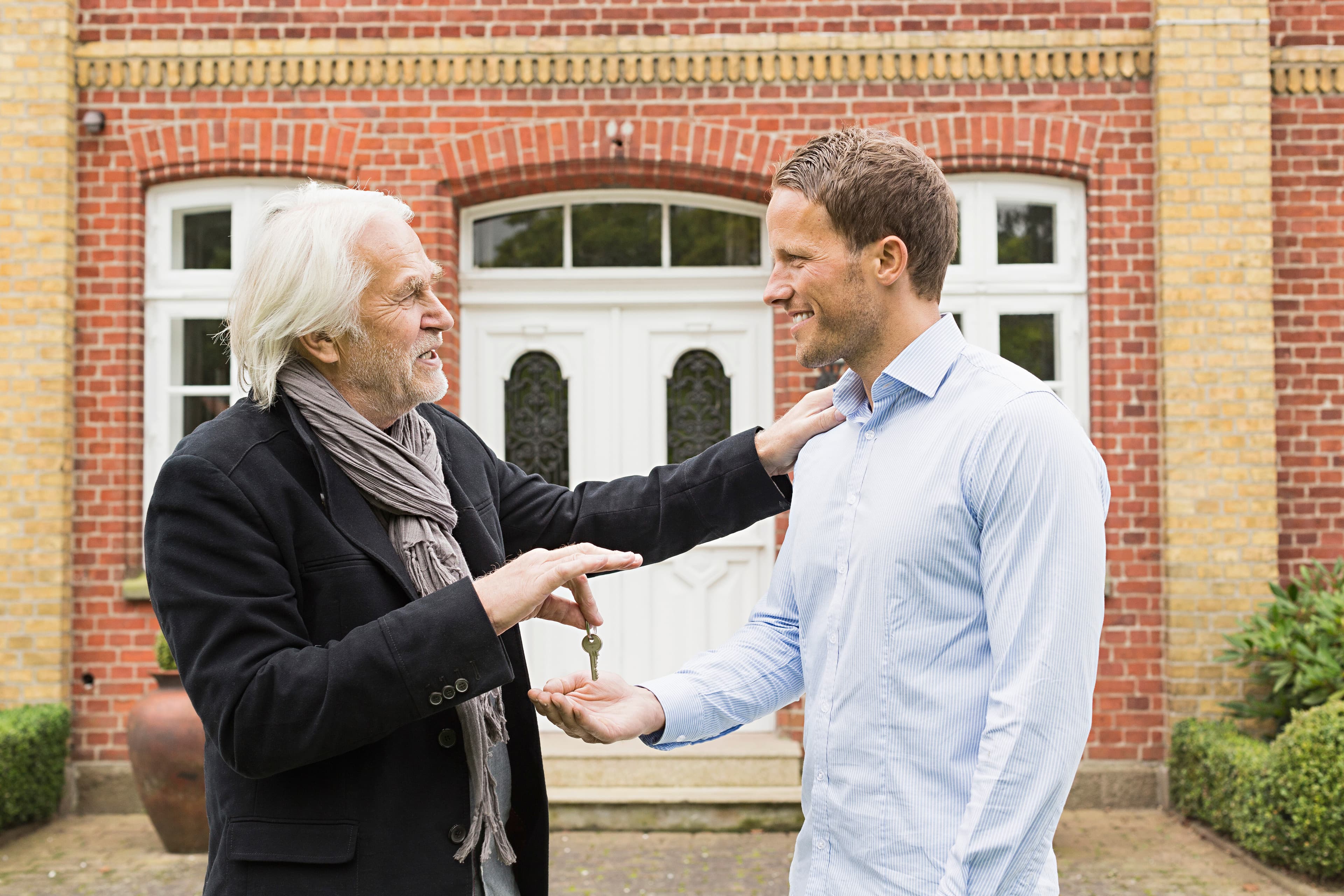 Father giving son a key outside their new house